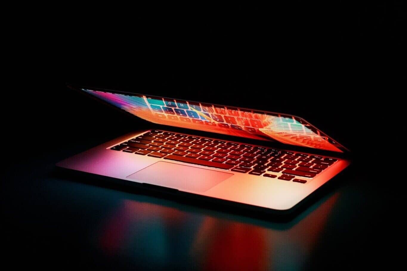 Partially closed laptop on black desk and black background