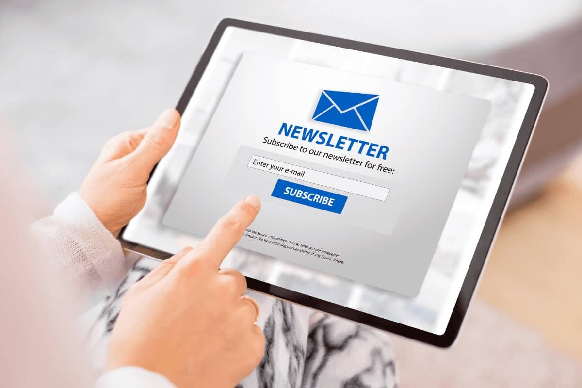 person holding tablet computer with a screen to subscribe to an email newsletter