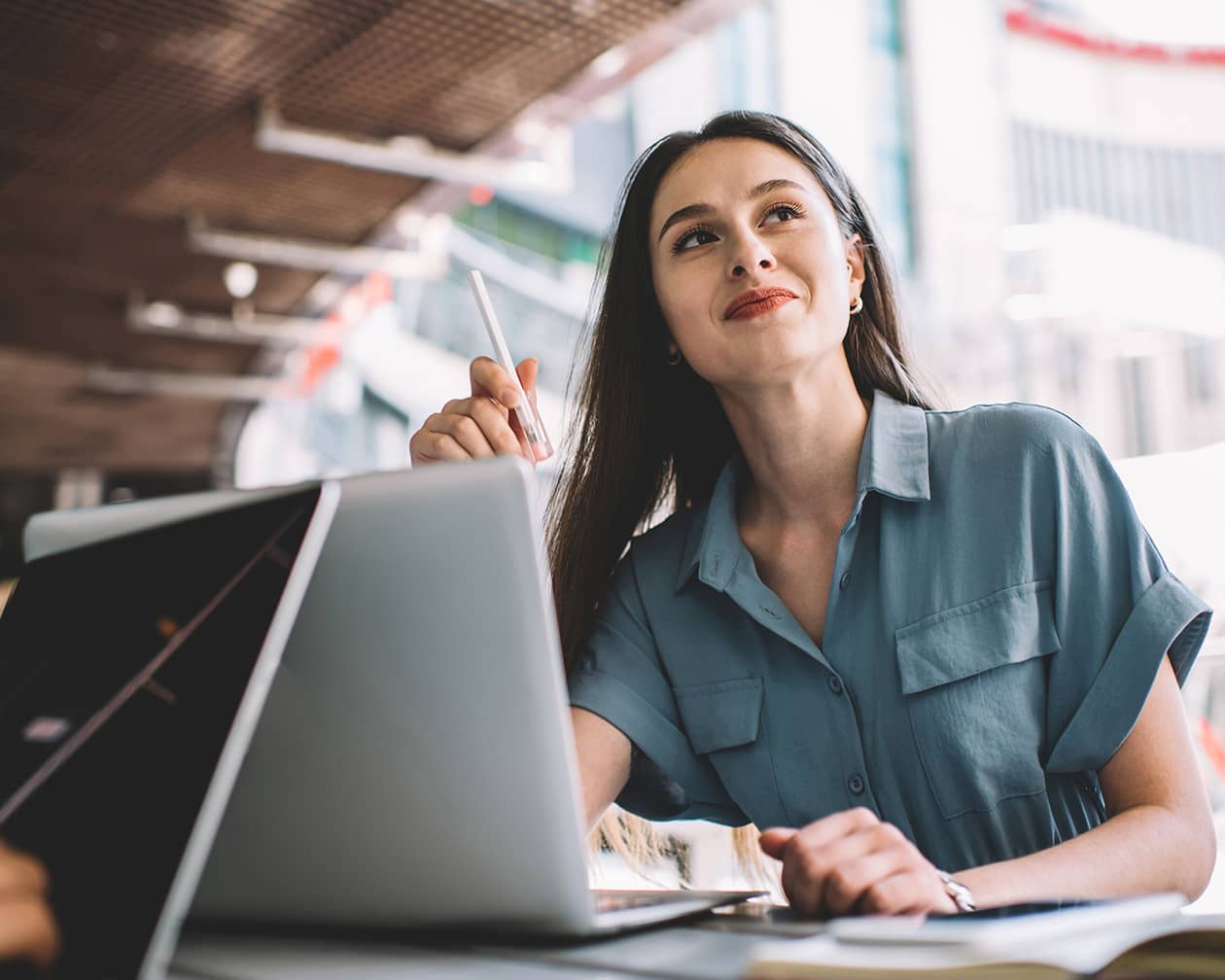 brown haired woman smiling and looking up from laptop