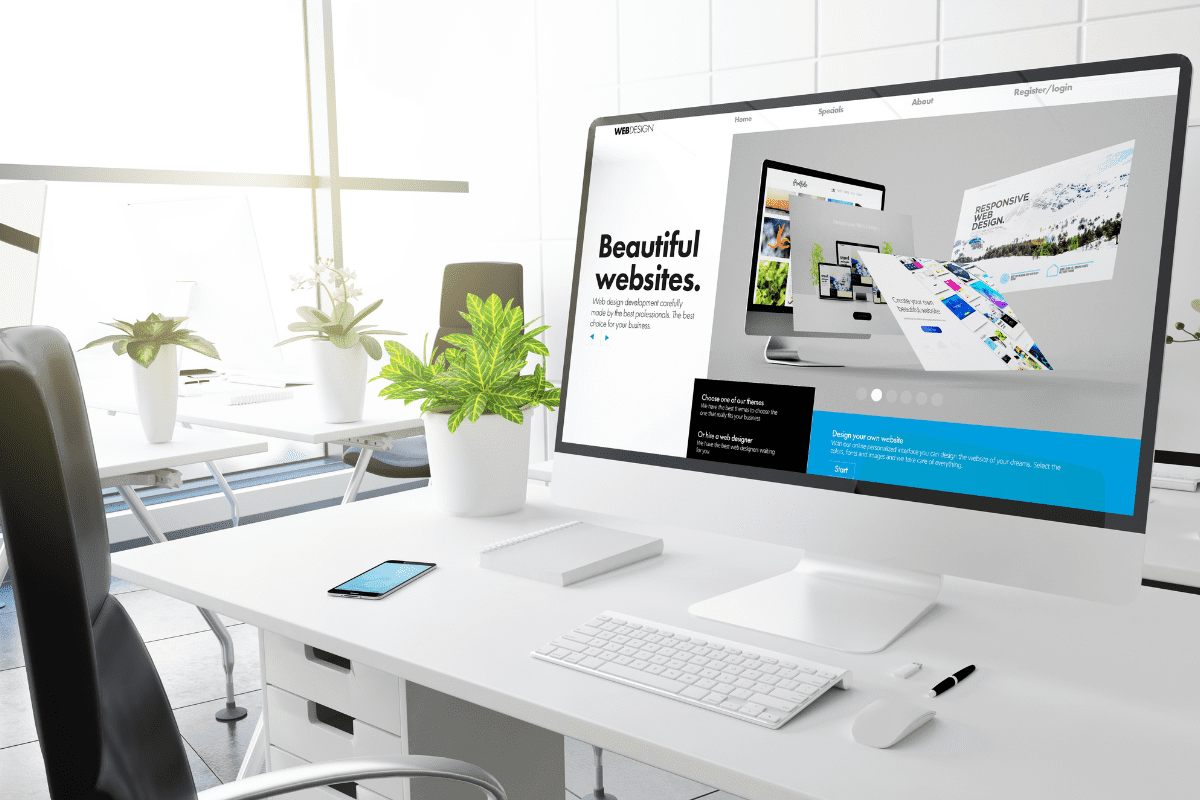 white desk with several plants and a keyboard and phone with large computer monitor with the words beautiful websites on it