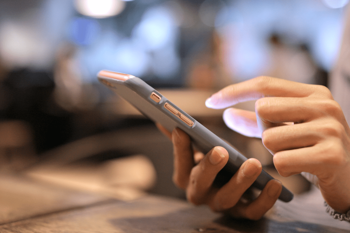 hand resting on a table using mobile phone