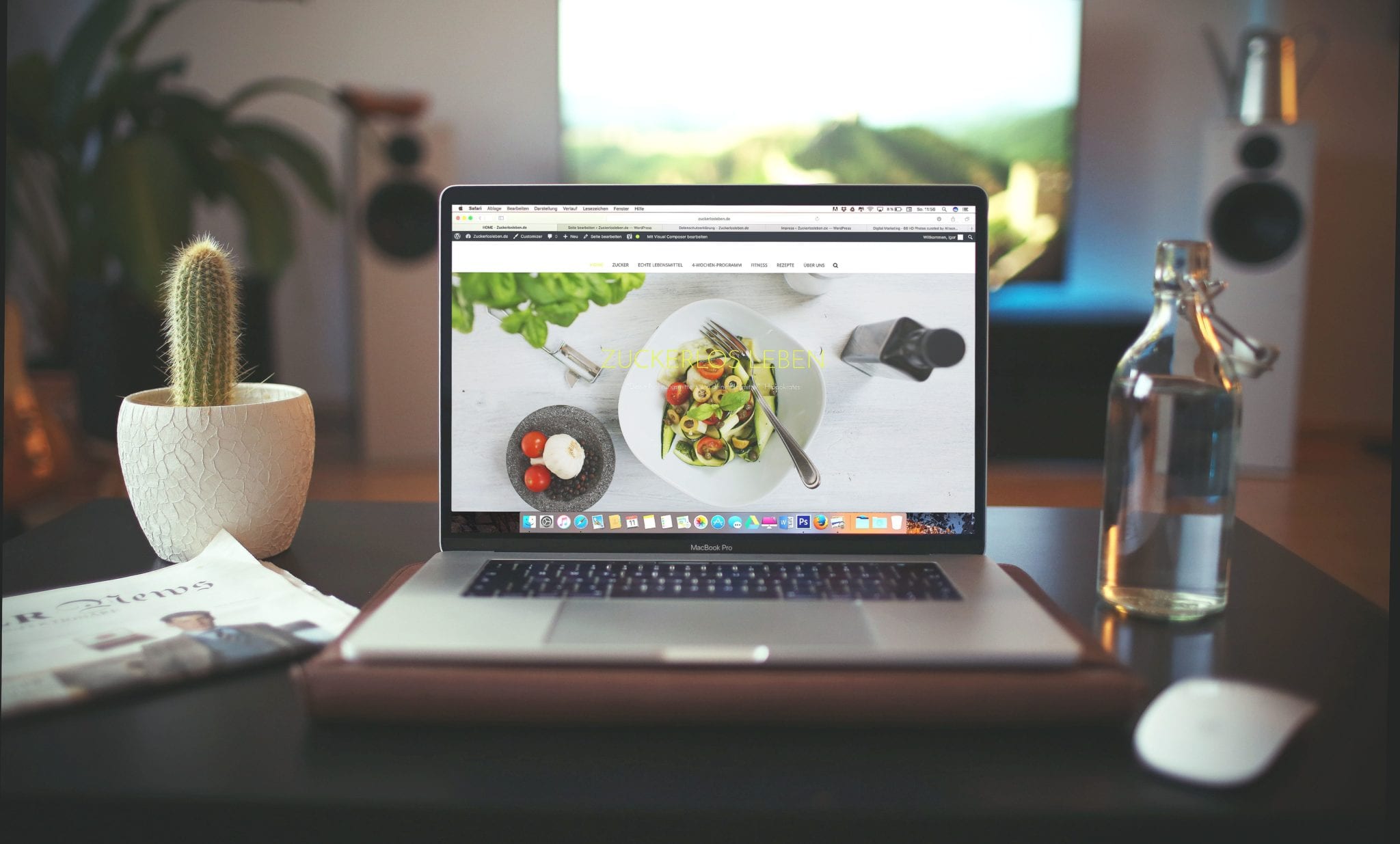 desk with laptop and newspaper with food website showing