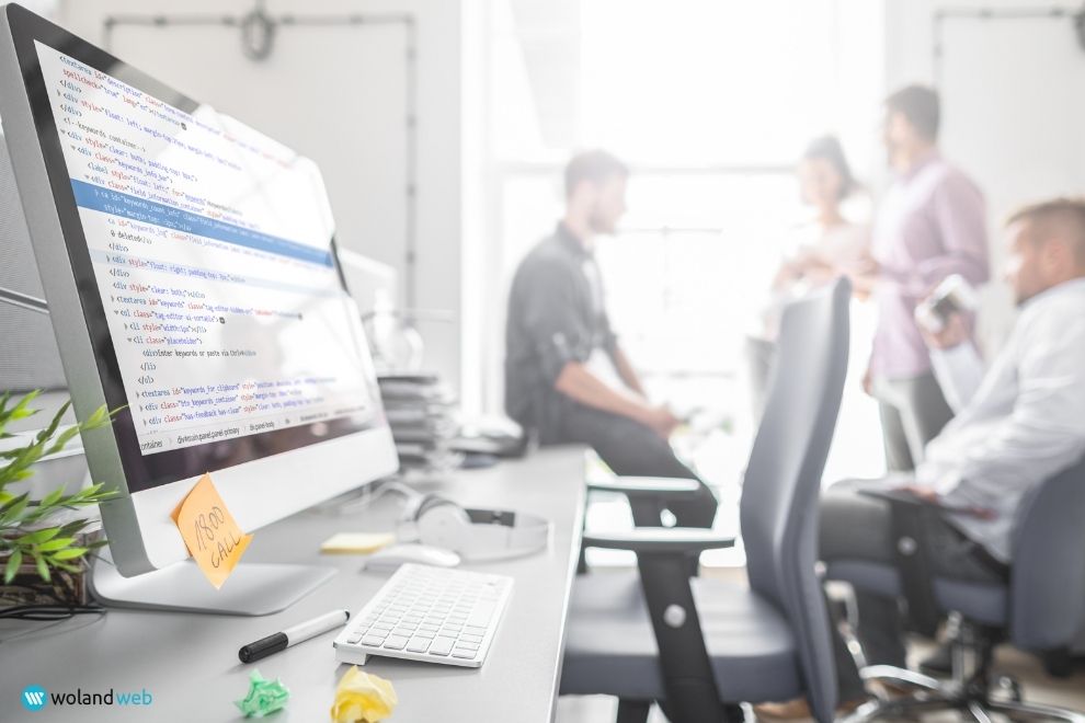 computer monitor with website code in front of a blurred group of people in an office
